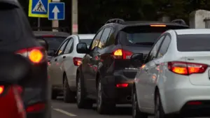 Automašīnas Rīgas ielās, kuras stāv sastrēgumā un gaida tālāko kustību pilsētā.