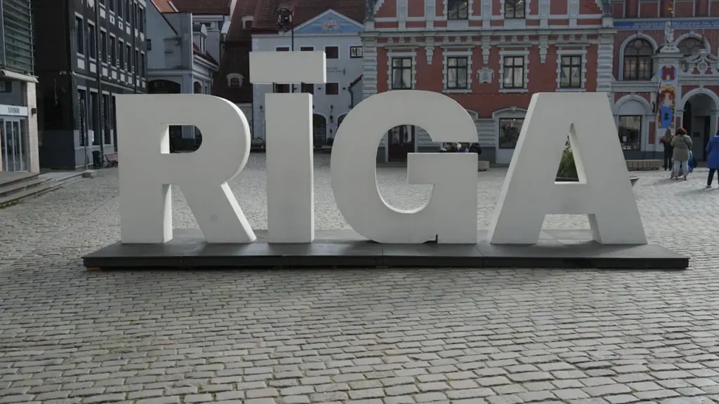 Liels baltu burtu uzraksts RĪGA uz bruģētas ielas vecpilsētas centrā.