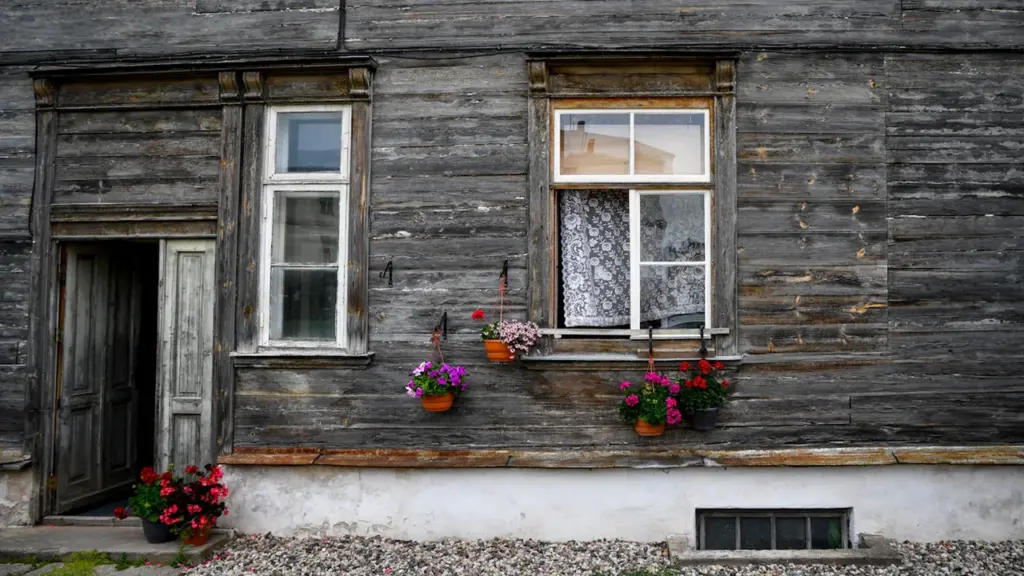 Koka māja ar puķu podiem pie logiem Valmieras lauku sētas tradicionālajā stilā.