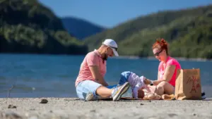 Ģimene atpūšas pie ezera saulainā dienā, ideāla vieta brīvdienu pastaigām.