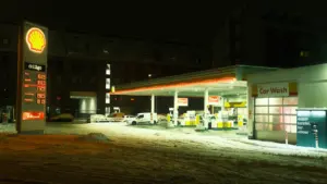 Degvielas uzpildes stacija vakarā ar sniegu, ilustrējot brauciena izmaksas un degvielas patēriņu.