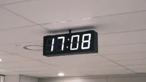 Digitālais sienas pulkstenis rāda precīzu laiku, kas simbolizē laika maiņu ceļojumu laikā.